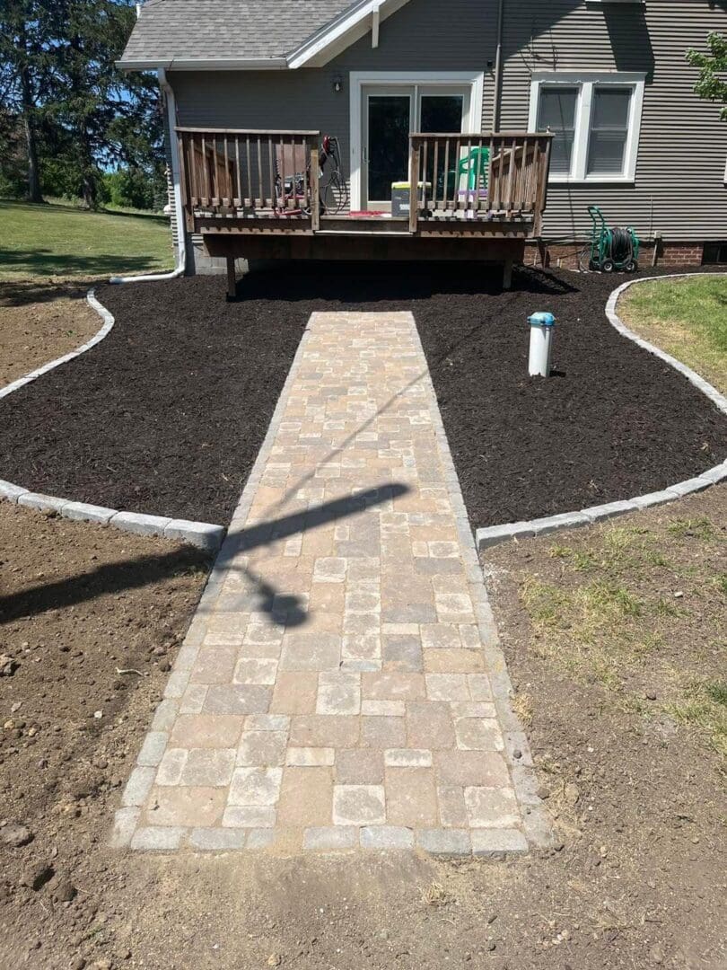 A walkway in the middle of a yard with mulch.